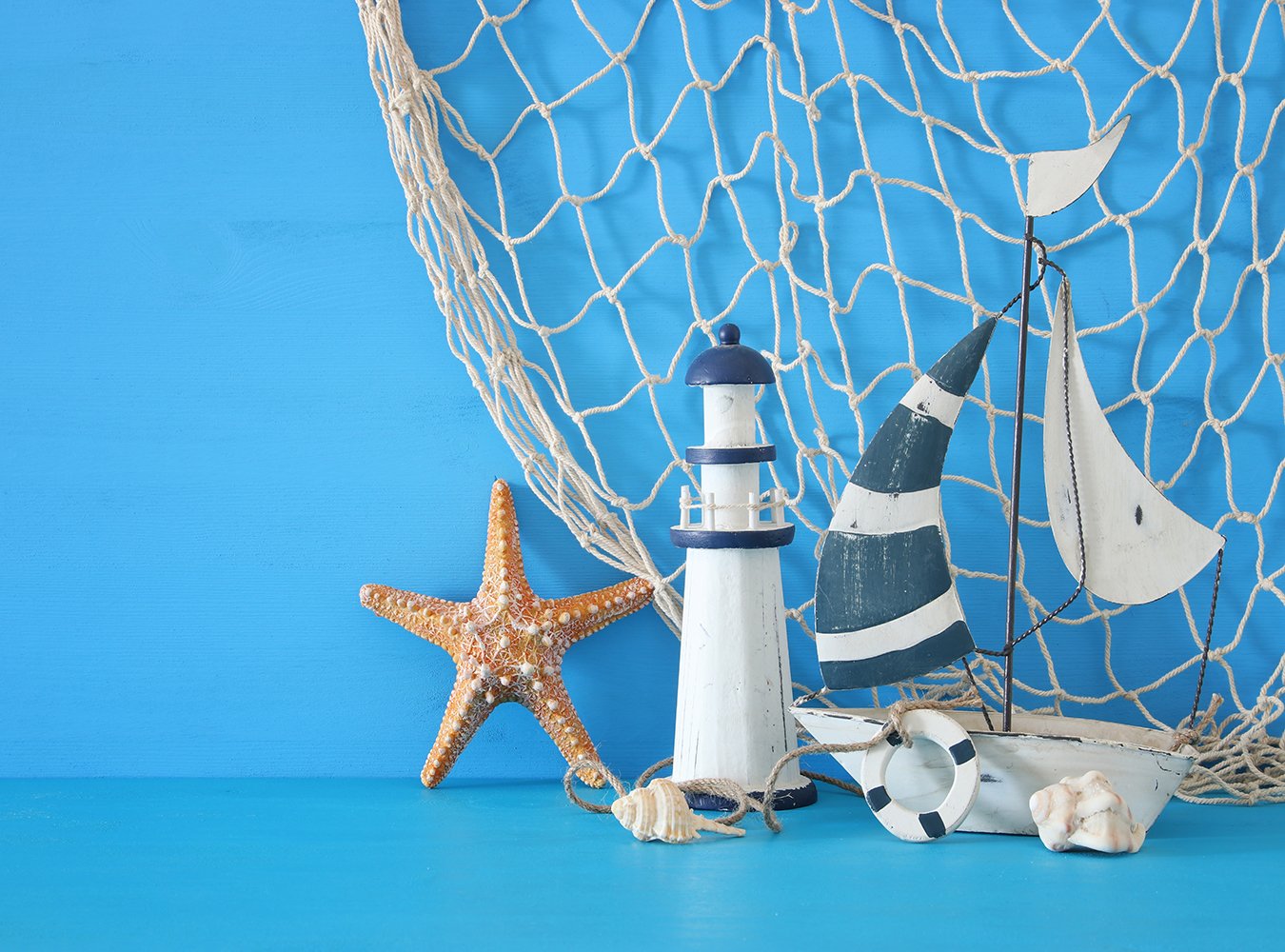 Blue Background Sailboat Lighthouse Starfish Shells and Fishnet